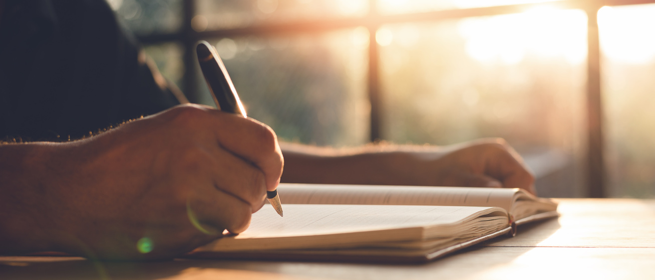 Stock photo of person writing in a notebook
